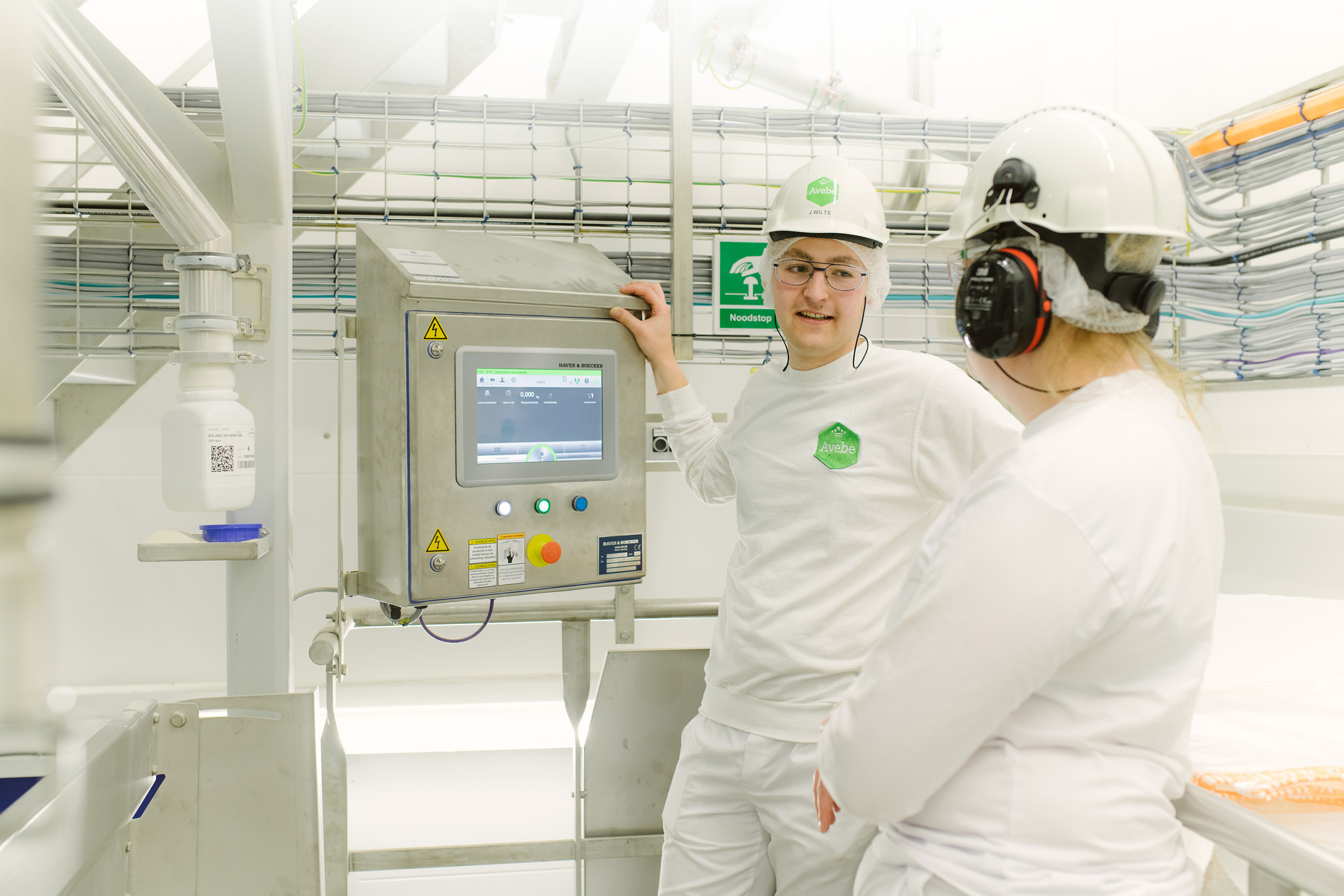 Een jonge medwerker in een winkel staat achter een tafel en vouwt denim broeken. Ze heeft een glimlach op haar gezicht.
