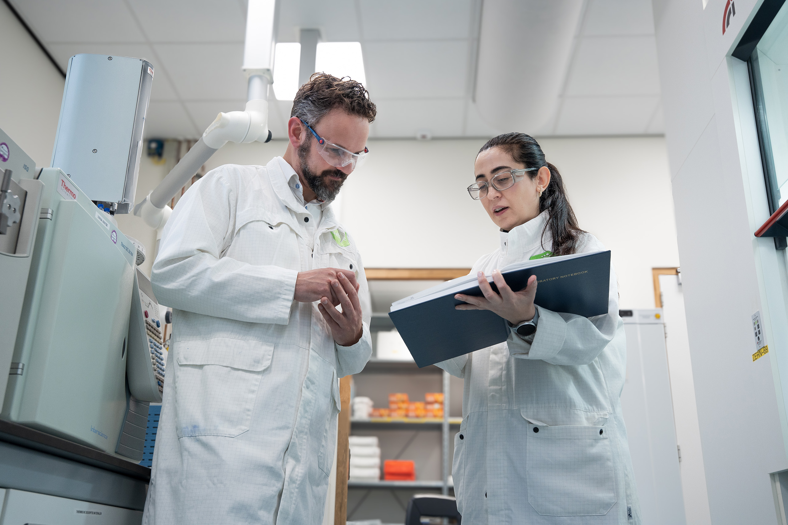 Vrouw in winkel glimlacht met een mobiel in haar hand.